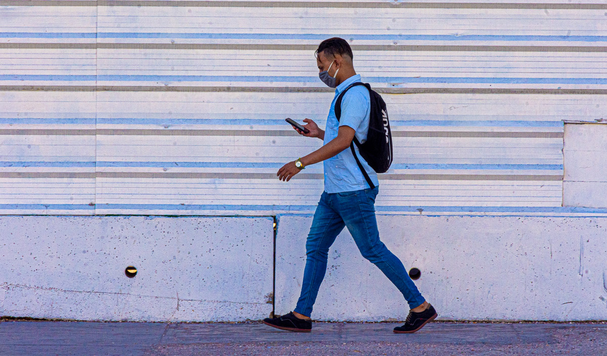 Joven cubano con mascarilla camina frente al Teatro Payret.