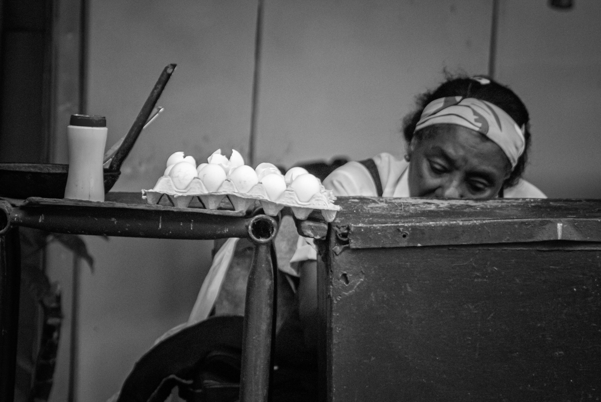Mujer detrás de un mostrador junto a una bandeja de huevos en un mercado de Cuba.