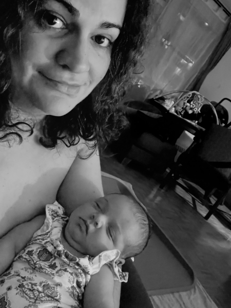  Mujer con expresión ambigua sosteniendo a su bebé dormido en brazos.