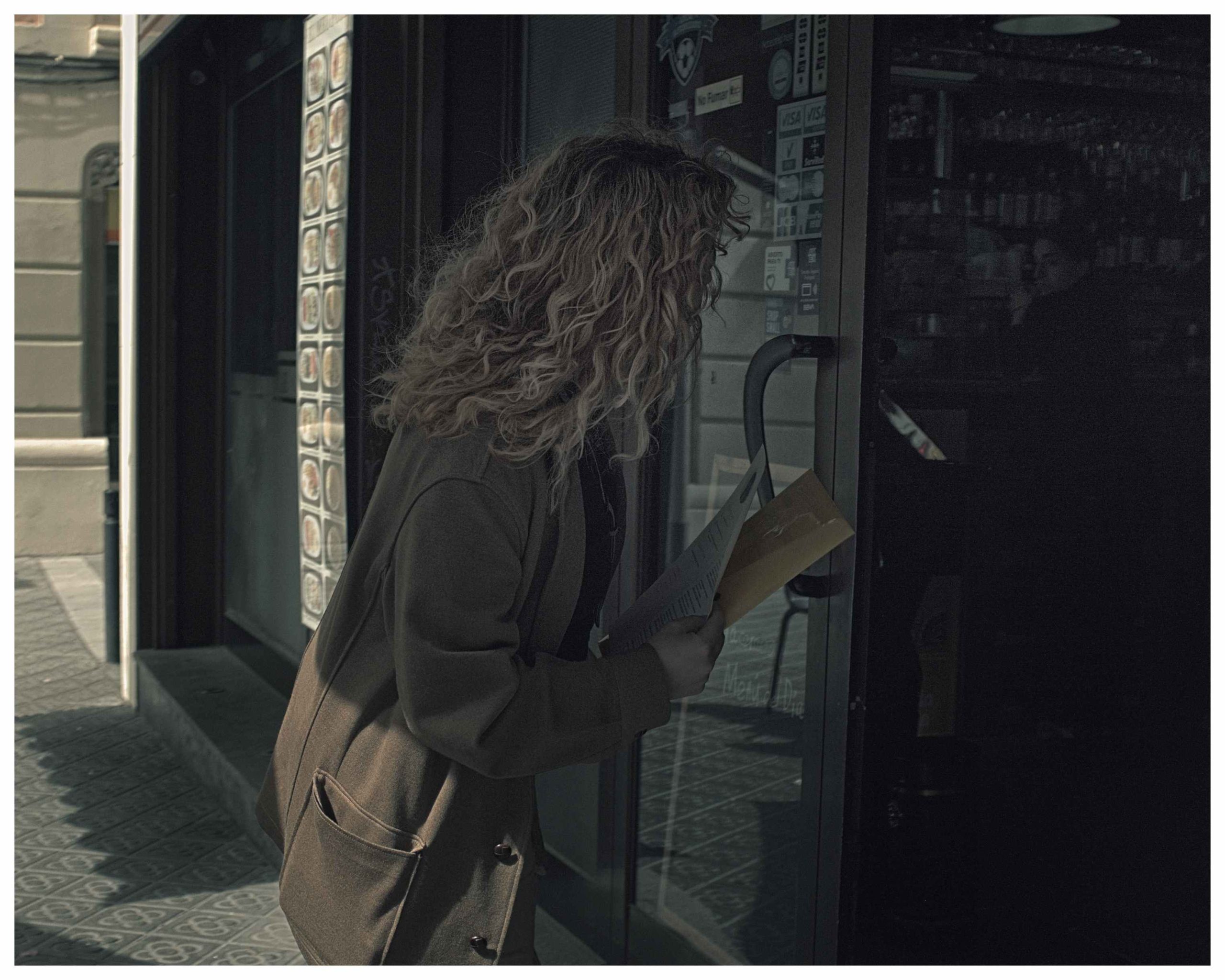 Mujer migrante entregando currículum en la puerta de un local.