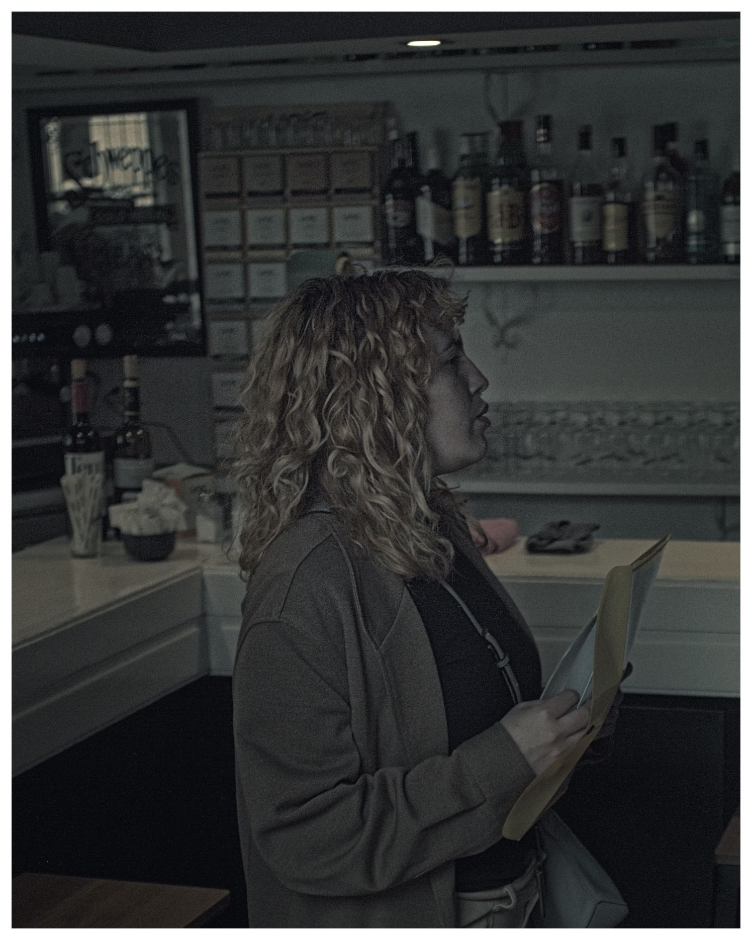 Mujer migrante en el interior de un bar, hablando con alguien fuera de plano.