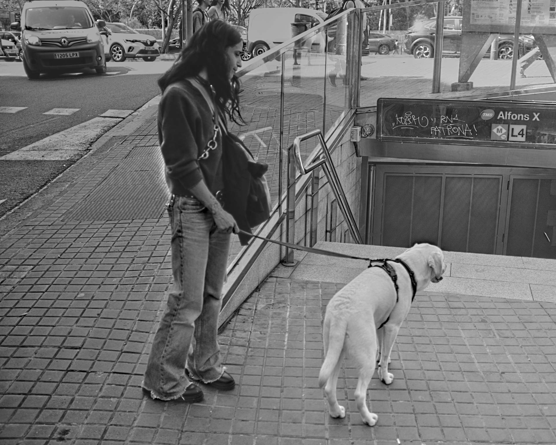 Una mujer con su perro frente a una estación de metro cerrada.