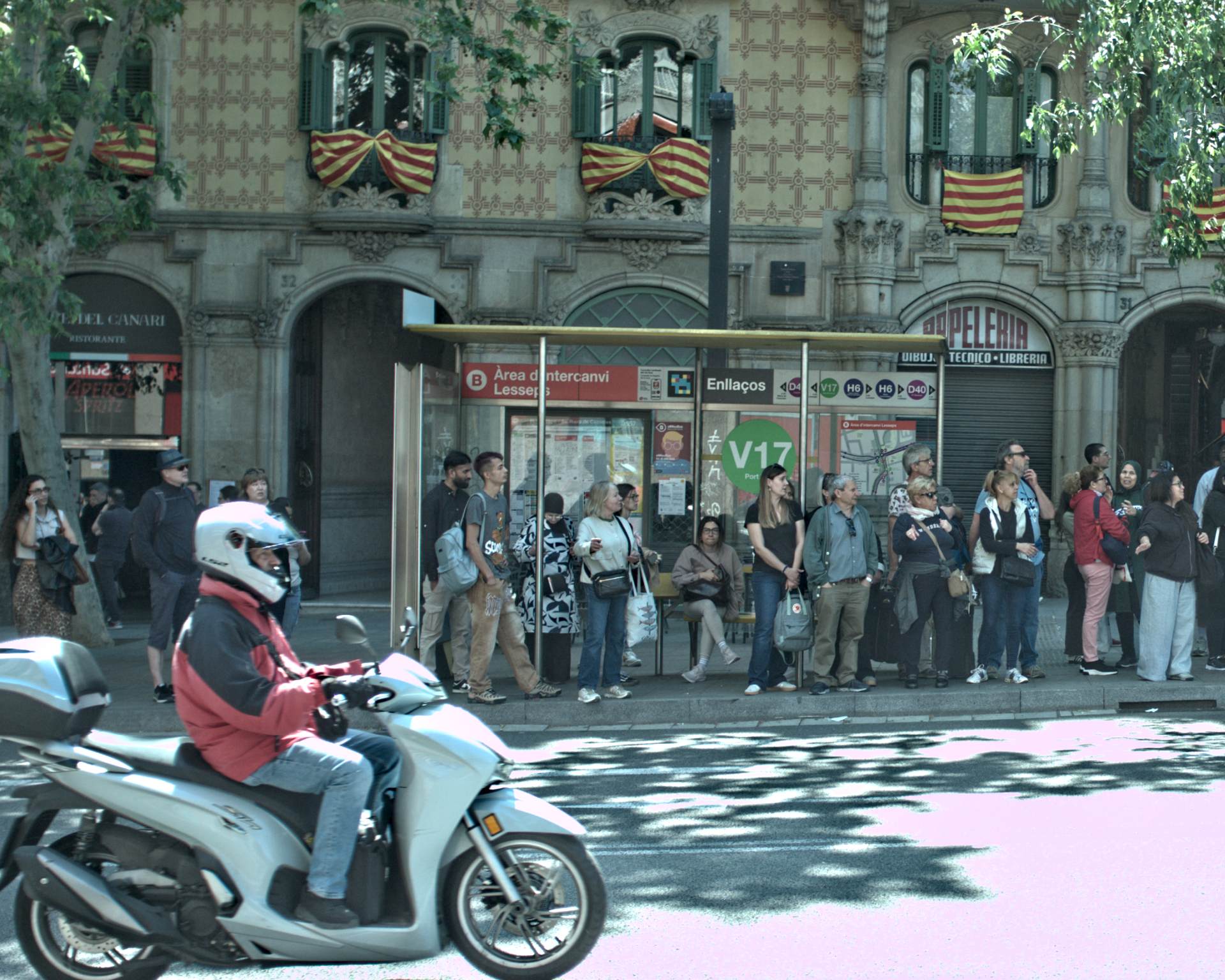 Multitud en una parada de autobús bajo el sol en Barcelona.