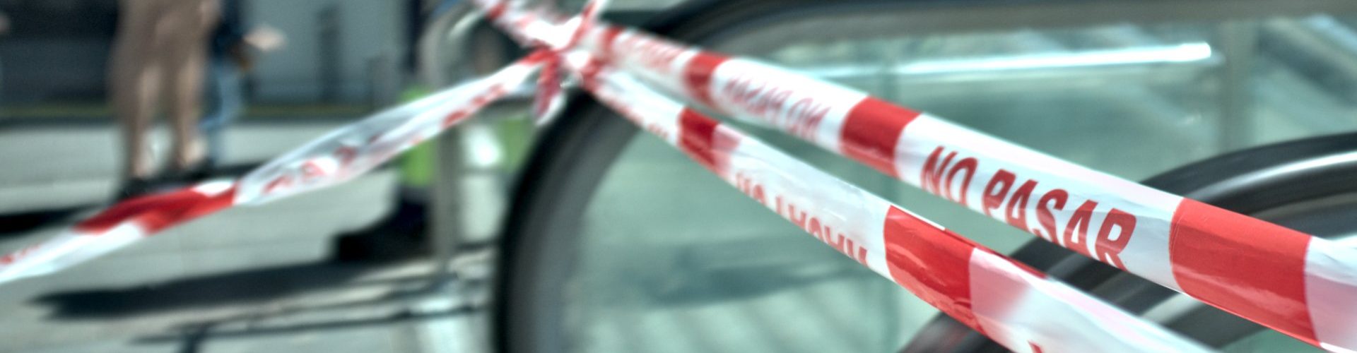 Cinta de “No pasar” bloquea una escalera mecánica en una calle urbana.