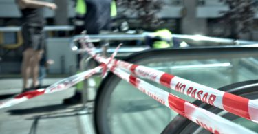 Cinta de “No pasar” bloquea una escalera mecánica en una calle urbana.