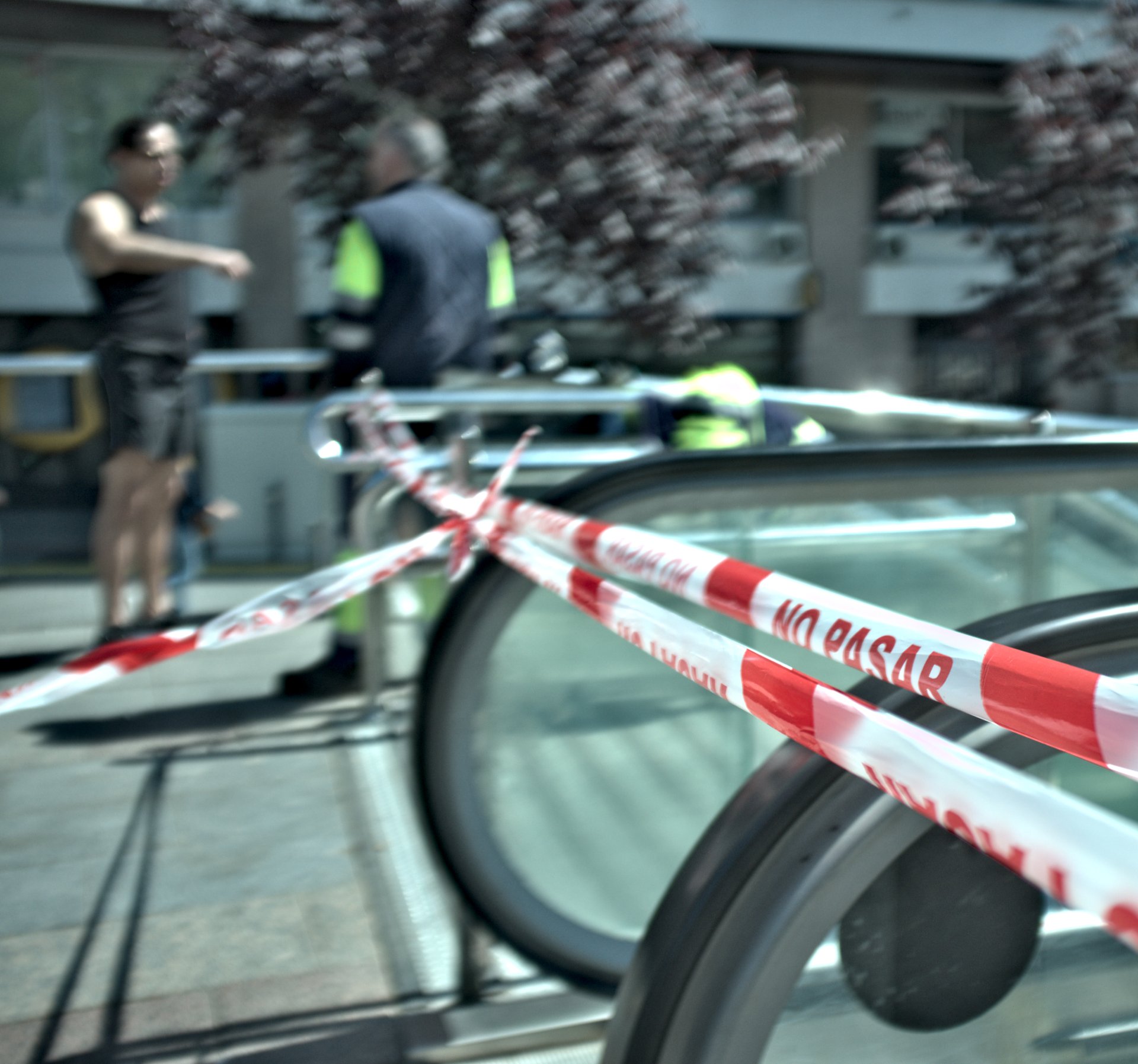 Cinta de “No pasar” bloquea una escalera mecánica en una calle urbana.